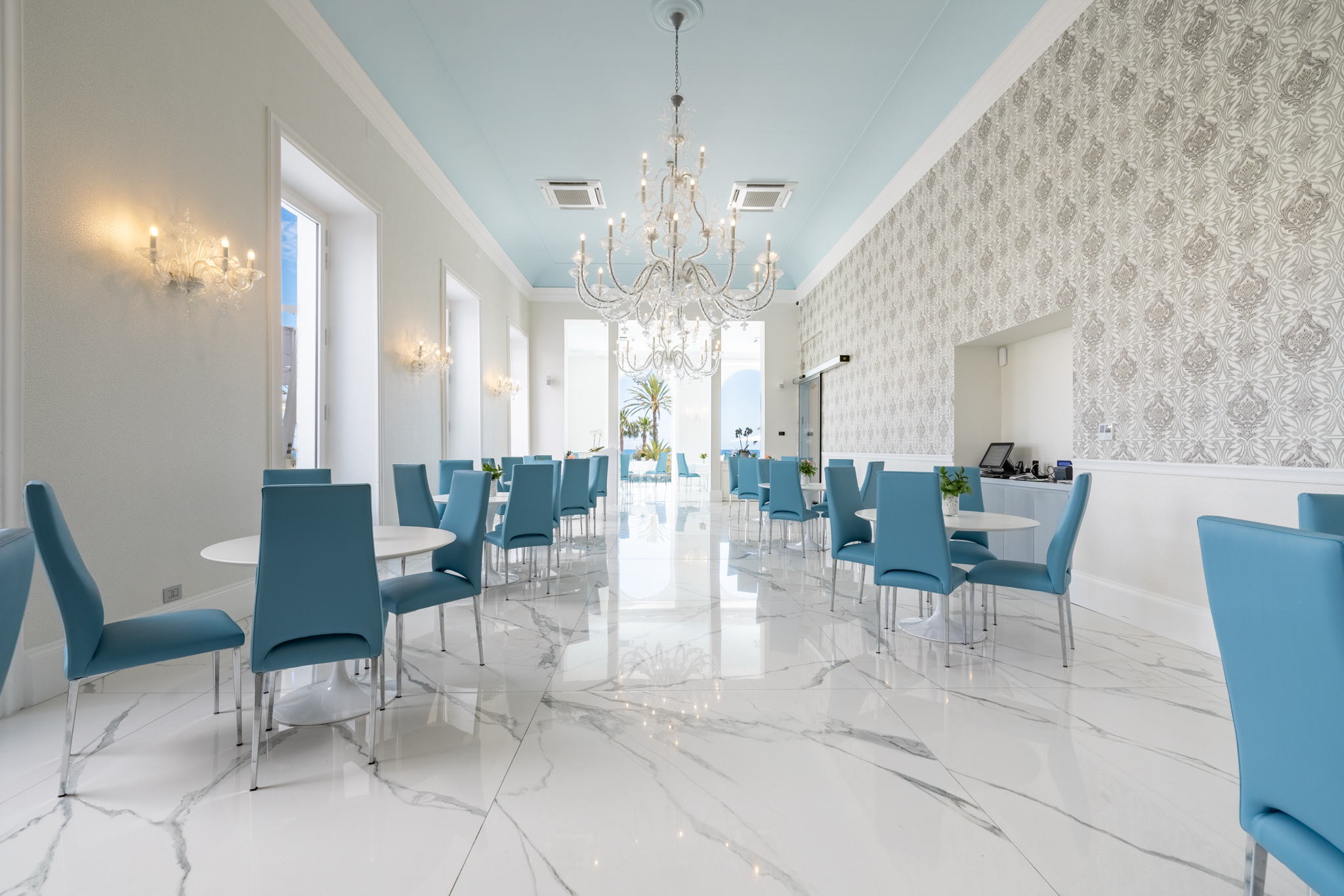 Sala Aqualua con tavoli, lampadari e prospettiva verso il mare